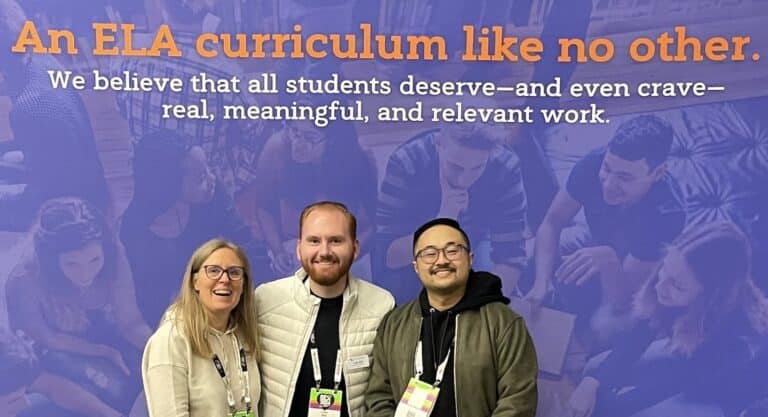 Three people smiling in front of a purple backdrop that reads, An ELA curriculum like no other. We believe that all students deserve—and even crave—real, meaningful, and relevant work. Captured at the NCTE Annual Convention, this moment reflects our shared commitment to innovative education.
