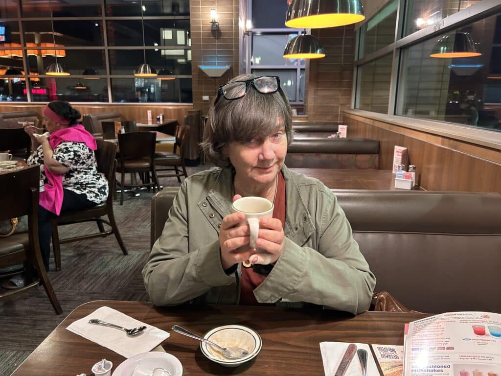 A woman seated at a restaurant table enjoys a cup of coffee.