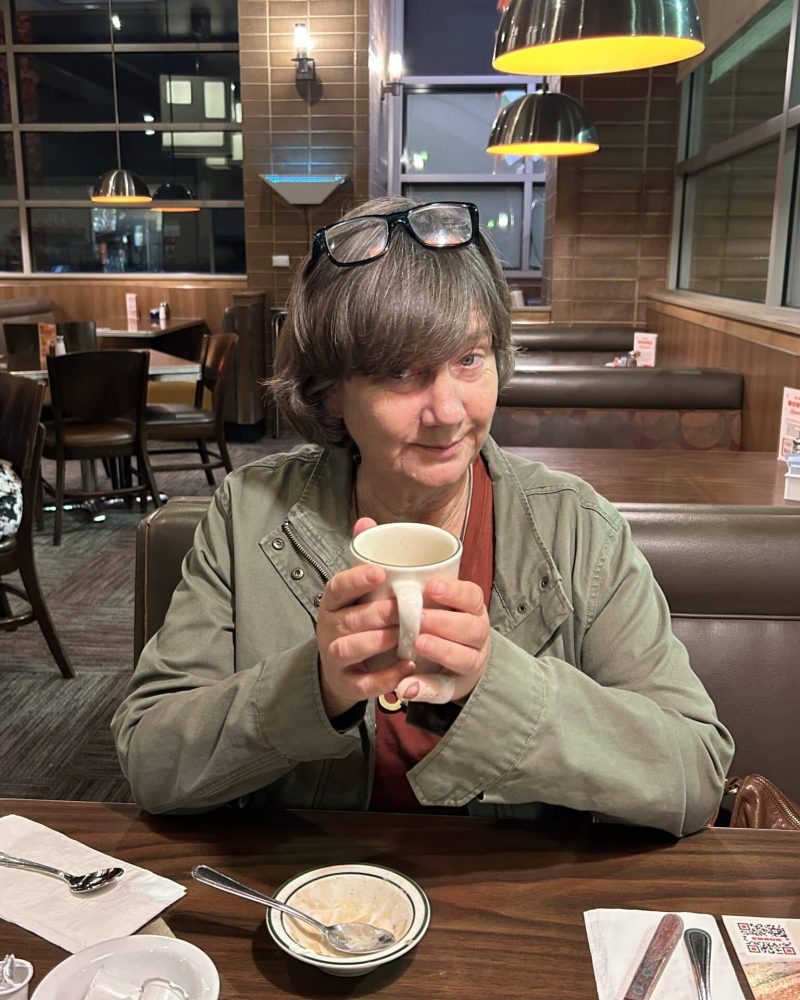A woman seated at a restaurant table enjoys a cup of coffee.